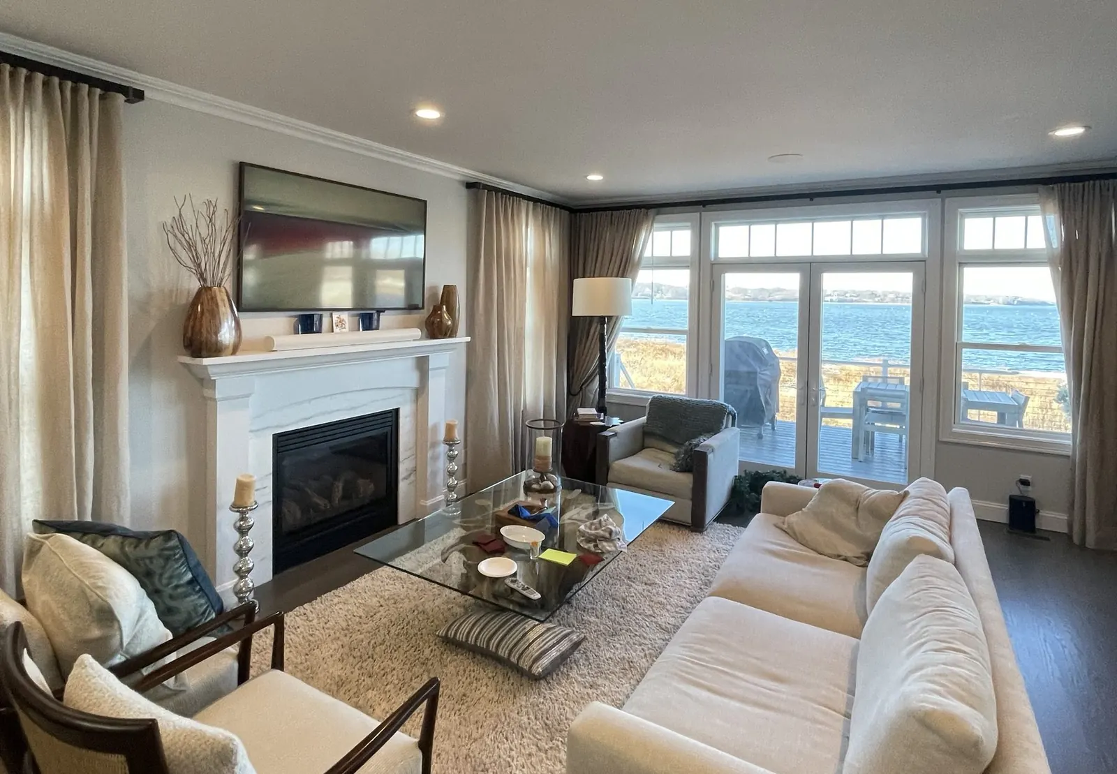 Bright coastal living room with a wall-mounted TV over the fireplace
